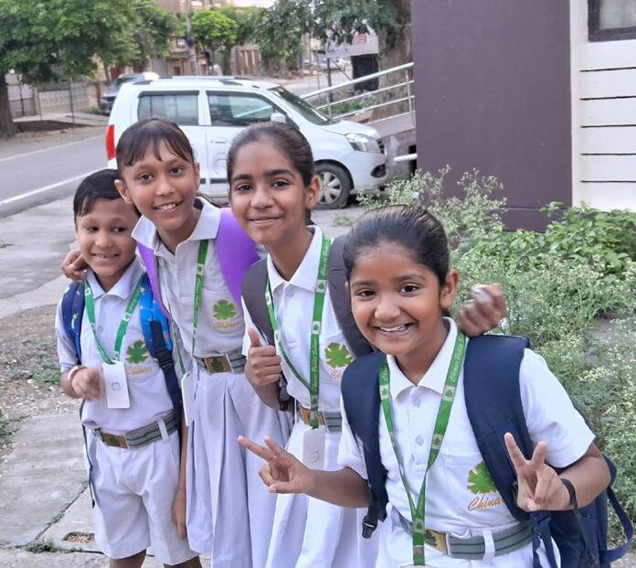 बैग लेकर बस स्टॉप पर इंतजार करते बच्चे