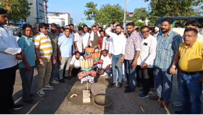 सड़क के गड्ढे भरकर विरोध प्रदर्शन करते कांग्रेस कार्यकर्ता